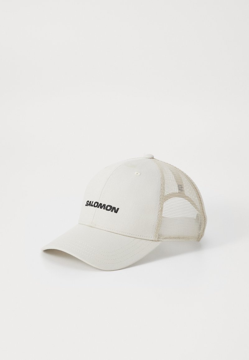 Caps med strukturert front og mesh bak, i beige med buet brem og svart "SALOMON"-logo på forsiden.