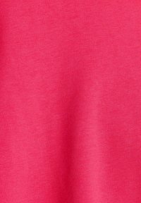 Gros plan sur un tissu rose vif, lisse et finement tissé, montrant une texture délicate et un léger jeu d'ombres lumineuses.