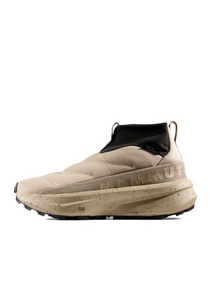 Scarpa da trekking beige slip-on con polsino nero alla caviglia, suola grossa maculata e branding MAMMUT in rilievo sul lato.
