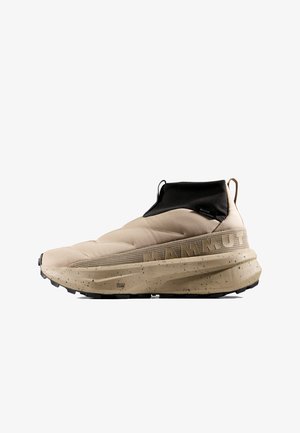 Beige instapschoen voor wandelen met zwarte enkelboord, grove gevlekte zool en verhoogd MAMMUT-logo aan de zijkant.