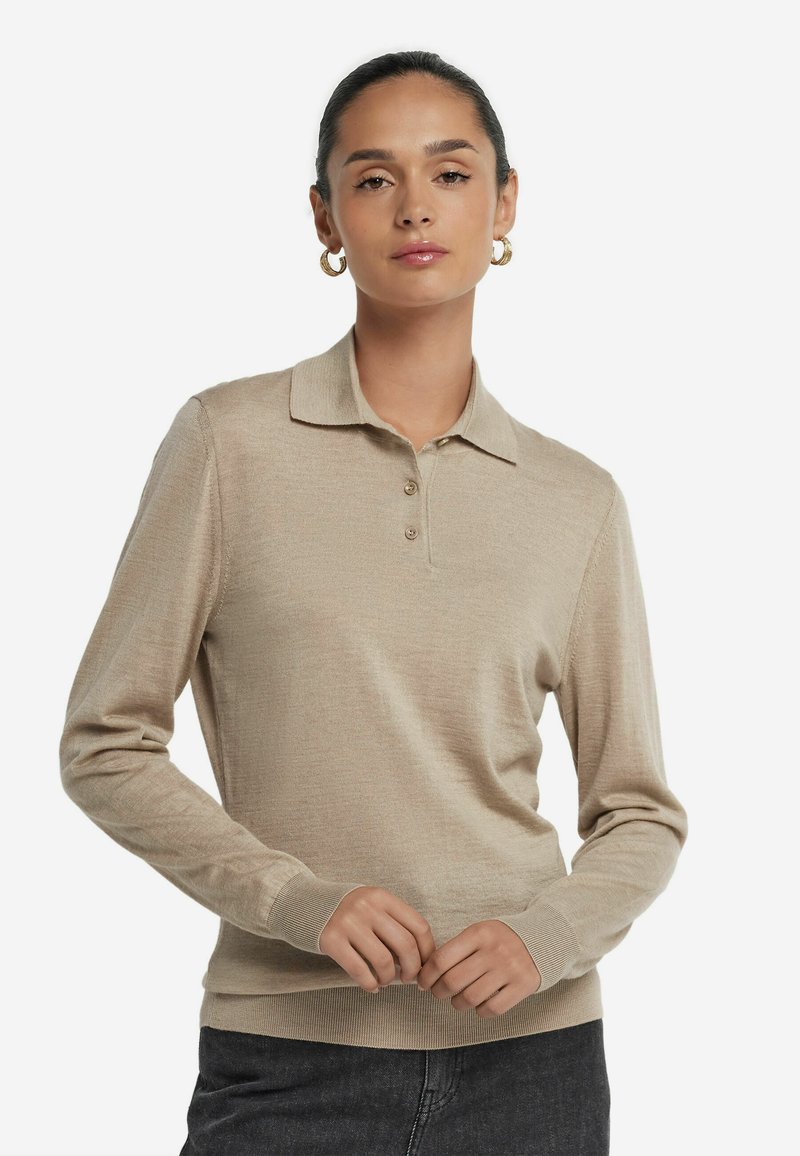 Beige långärmad polo med krage, tre knappar i placket och ribbad nederkant och ärmslut. Mjuk textur, figurformad design, minimalistisk stil.