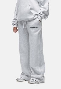 Lichtgrijze joggingbroek van zacht materiaal met een ontspannen pasvorm, voorzien van zijzakken en de tekst "GOODFORNOTHING" op de dij.