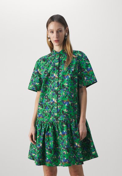 Abito verde floreale con maniche corte, chiusura frontale a bottoni e orlo arricciato. Il tessuto presenta diverse tonalità di verde, blu e nero in un design a motivi.