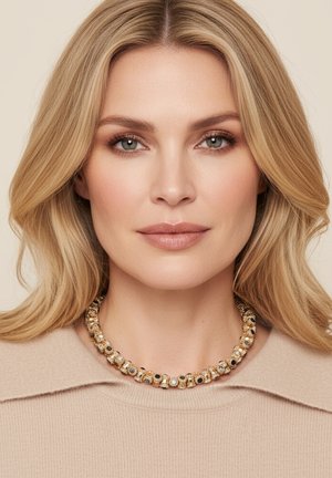 Goudkleurige ketting met afwisselend ronde kralen met zwarte en parelaccenten. Geplaatst tegen een neutrale achtergrond.