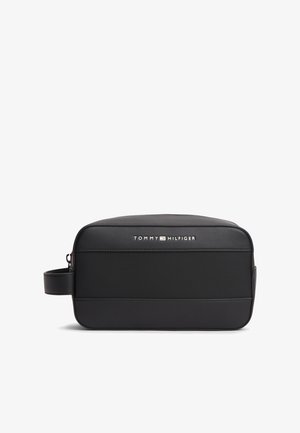 Črna pravokotna toaletna torbica z bočnim ročajem, teksturirano sprednjo ploščo in logotipom "Tommy Hilfiger" v belem in rdečem na zgornjem sprednjem delu.