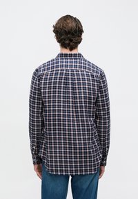 Tengerészkék kockás ing világos rózsaszín és krémszínű rácsmintával, gombos gallérral, hosszú ujjakkal és ívelt szegéllyel.