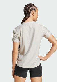 Camiseta atlética de manga corta de color gris claro con un acabado texturizado, combinada con pantalones cortos de rendimiento negros. Diseño simple, estilo minimalista.