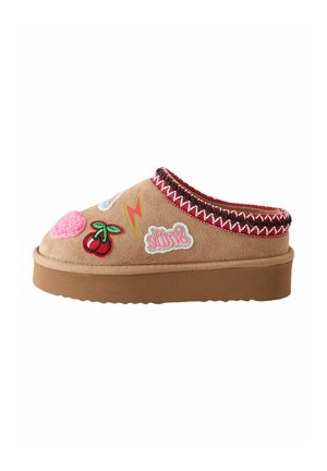 Brune slip-on slippers med tyk sål, dekoreret med patches, inklusive kirsebær, et lyn, et pink hjerte og ordet "smile."
