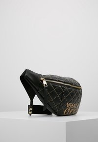 Black quilted leather fanny pack with gold hardware, featuring a zip closure and the text "VERSACE COUTURE" embossed on the front.