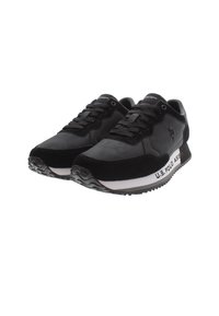 Zapatos deportivos negros con un upper de cuero liso y gamuza, que presentan una media suela blanca, cordones negros y un logo en el lateral. Suela texturizada.