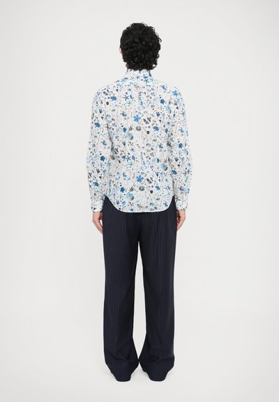 Fehér alapon virágmintás ing kék és fekete mintákkal; hosszú ujjú, íves szegélyű, nyaknál gombos megoldással. Csíkos nadrággal párosítva.