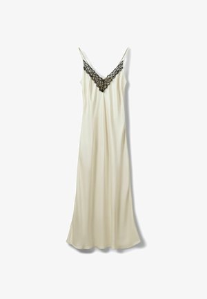 Elfenbeinfarbiges langes Satinkleid mit dünnen Trägern und schwarzer Spitzenverzierung entlang des V-Ausschnitts.