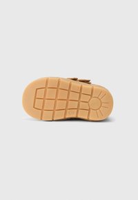 Sola de borracha castanha com um padrão de aderência texturizado e detalhes circulares, apresentando formas de bloco e uma ligeira elevação para tração.