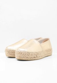 Espadrillas dorate metalliche realizzate in pelle con suola in corda di juta. Presentano un design slip-on e una punta arrotondata. Texture liscia.