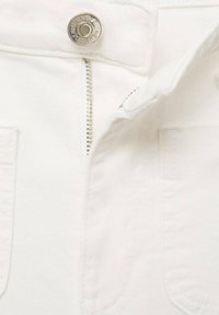 Jeans de mezclilla blanca con un cierre de cremallera plateado, un botón metálico en la parte frontal y bolsillos delanteros con una textura suave y lisa.