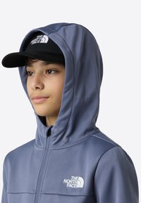 Μπλούζα φούτερ με κουκούλα σε ανοιχτό μπλε ύφασμα με ομαλή υφή, που διαθέτει φερμουάρ εμπρός και λευκό λογότυπο. Μαύρο καπέλο με ορατό λογότυπο.