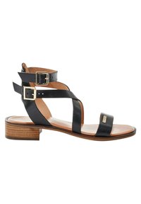 Sandalias de cuero negro con correas de tobillo ajustables y acentos de doble hebilla. Tacón de bloque de madera plano. Plantilla suave en tono marrón.