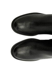 Czarne skórzane buty z fakturowanym wykończeniem, okrągłym noskiem i widocznym szyciem wzdłuż podeszwy, widziane z perspektywy z góry.