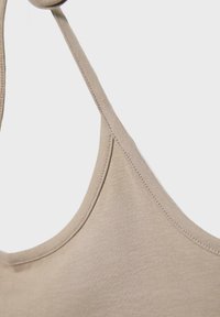 Gros plan d'un tissu beige avec une fine bride, montrant une texture lisse et un détail de couture soignée.