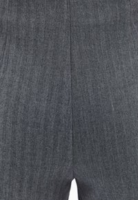 Tissu gris à motif en chevrons avec une texture lisse. Présente des rayures verticales et est taillé dans une coupe ajustée.