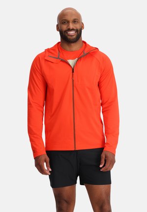Lichtgewicht herenjack, met rits, in feloranje met een textuur, een capuchon en grijze details. Draag het over een bijpassend shirt en zwarte shorts.