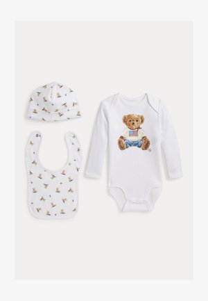 Ensemble bébé blanc avec body à manches longues avec un ours en peluche en jean et chemise avec drapeau, chapeau assorti et bavoir avec petits imprimés d'oursons.