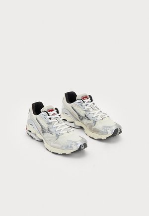 Valged võrkmaterjalist tenis jad, millel on hõbedased aktsendid, tekstureeritud ülaosa, must pehme krae, valged nöörid ja kummist vaikne tall koos erilise mustriga.