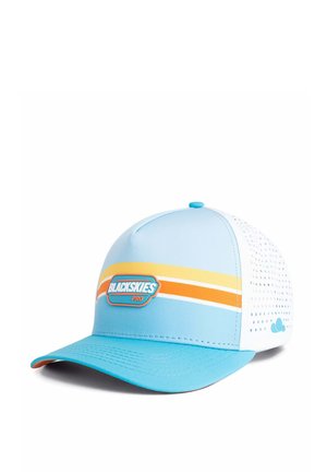 Woman with long dark hair wears white and blue cap with yellow and orange stripes and "BLACKSKIES PRO" logo, white t-shirt, neutral background.