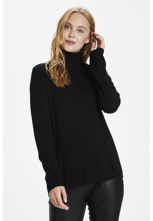 Pull à col roulé noir à manches longues en tricot doux, avec une coupe décontractée et un col en côtes. Porté avec un pantalon en cuir noir.