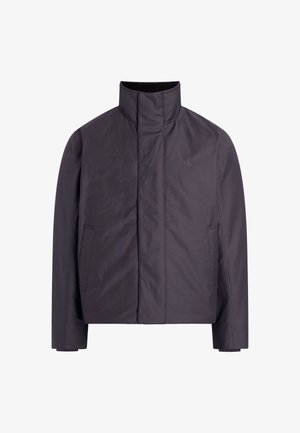 Tumehall hall vabaga, kõrge kaeluse, ees olevate taskutega ja sileda, veekindla tekstuuriga; sisaldab rinna peal diskreetset logo.