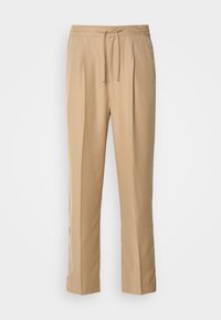 Lys beige bukser laget av glatt stoff, med strikk i livet, to legg foran og rette, løstsittende ben for komfort.