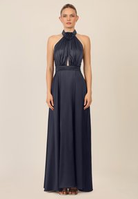 Marineblaues Satin-Halterkleid mit Ausschnitt vorne, BlumenDetail am Hals und einem fließenden, bodenlangen Rock. Glatte Textur insgesamt.