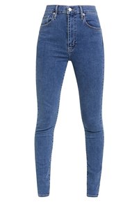 Jeans skinny a vita alta blu con bottone e cerniera frontale, passanti per cintura e tasche anteriori e posteriori, esposti su uno sfondo bianco.