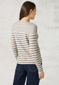 Pull rayé en beige et crème, avec un col rond, des manches longues et une silhouette ajustée, fabriqué en maille douce.
