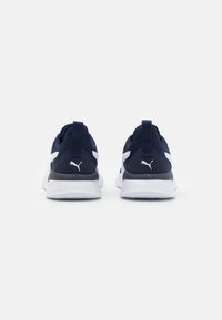Baskets de sport navy avec accents blancs et semelle intermédiaire noire texturée. Comprend un col rembourré et une languette pour un enfilage facile.