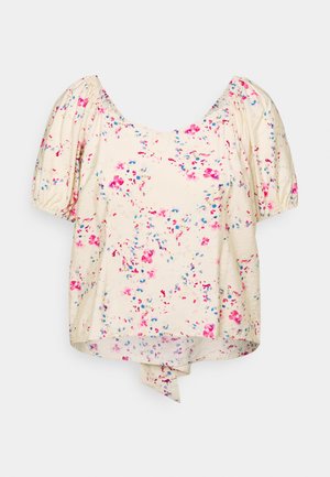 Crème blouse met roze en blauwe bloemmotieven, korte pofmouwen, een ronde halslijn en een klein strikdetail aan de voorkant.