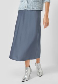 Grijze satijnen midi-rok met een gladde textuur, aangevuld met glanzende zilveren enkellaarsjes met een toegespitste neus en ritssluiting detail.