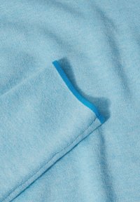 Tessuto blu cielo, con una texture liscia. La manica presenta un bordo blu a contrasto sul polsino, con un design casual.