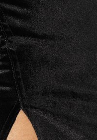 Musta samettihame, jossa on rypytyksiä sivulla ja leikattu osa, esittelee pehmeää rakennetta ja tyylikästä muotoilua.