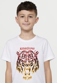 Baltas medvilninis marškinėliai su daugiaspalviu tigro grafiniu piešiniu raudonais ir oranžiniais tonais, viršuje su užrašu "KORÖSHI" ryškiomis raudonomis raidėmis.