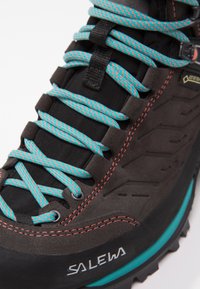Black suede hiking boot featuring turquoise and red laces, textured upper, reinforced eyelets, and a durable rubber sole with an accent stripe.