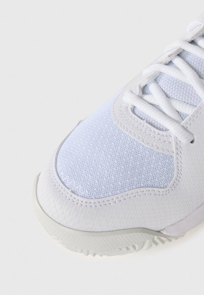 White athletic shoe with mesh fabric upper, textured accents, and a rubber sole. Features traditional lacing system and stitched detailing.