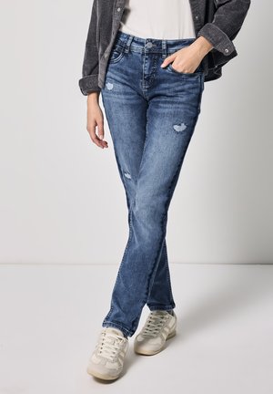 Blauwe denim jeans met een slim fit, met verweerde details, subtiele vervaging en een vijf-pocket ontwerp. Gecombineerd met lichtgrijze sneakers.