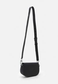 Svart axelremsväska med slät, matt yta, böjd form, justerbar rem och silverfärgade metallaccentdetaljer.