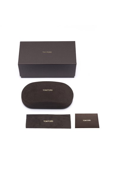 Hnědá pouzdro na brýle Tom Ford s hladkým, velurovým povrchem, zlatým logem, doplněné čisticí hadříkem a informační kartičkou, vše na bílém pozadí.