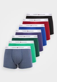 Una pila di sette boxer da uomo in nero solido, rosso, blu, viola, verde scuro, verde chiaro e a fantasia blu navy, tutti con cintura bianca Tommy Hilfiger.