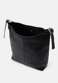 Borsa tote in pelle nera con una texture liscia, apertura superiore e tracolla regolabile. Presenta un design minimalista e un sottile dettaglio di cucitura.