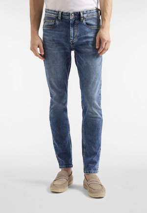 Niebieskie dżinsy z wyblakłymi miejscami i kontrastowym przeszyciem, z pięcioma kieszeniami, zamkiem błyskawicznym i krojem slim fit.