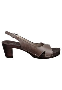 Sandale en cuir marron à talon ouvert, avec un design découpé courbé, de petits accents en métal ronds et un talon chunky en bois.