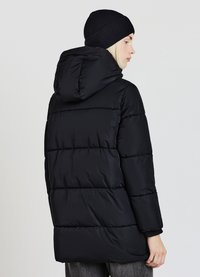 Piumino nero con cappuccio, caratterizzato da un design trapuntato, maniche lunghe e un taglio di lunghezza media. Abbinato a un berretto in maglia a coste nero.